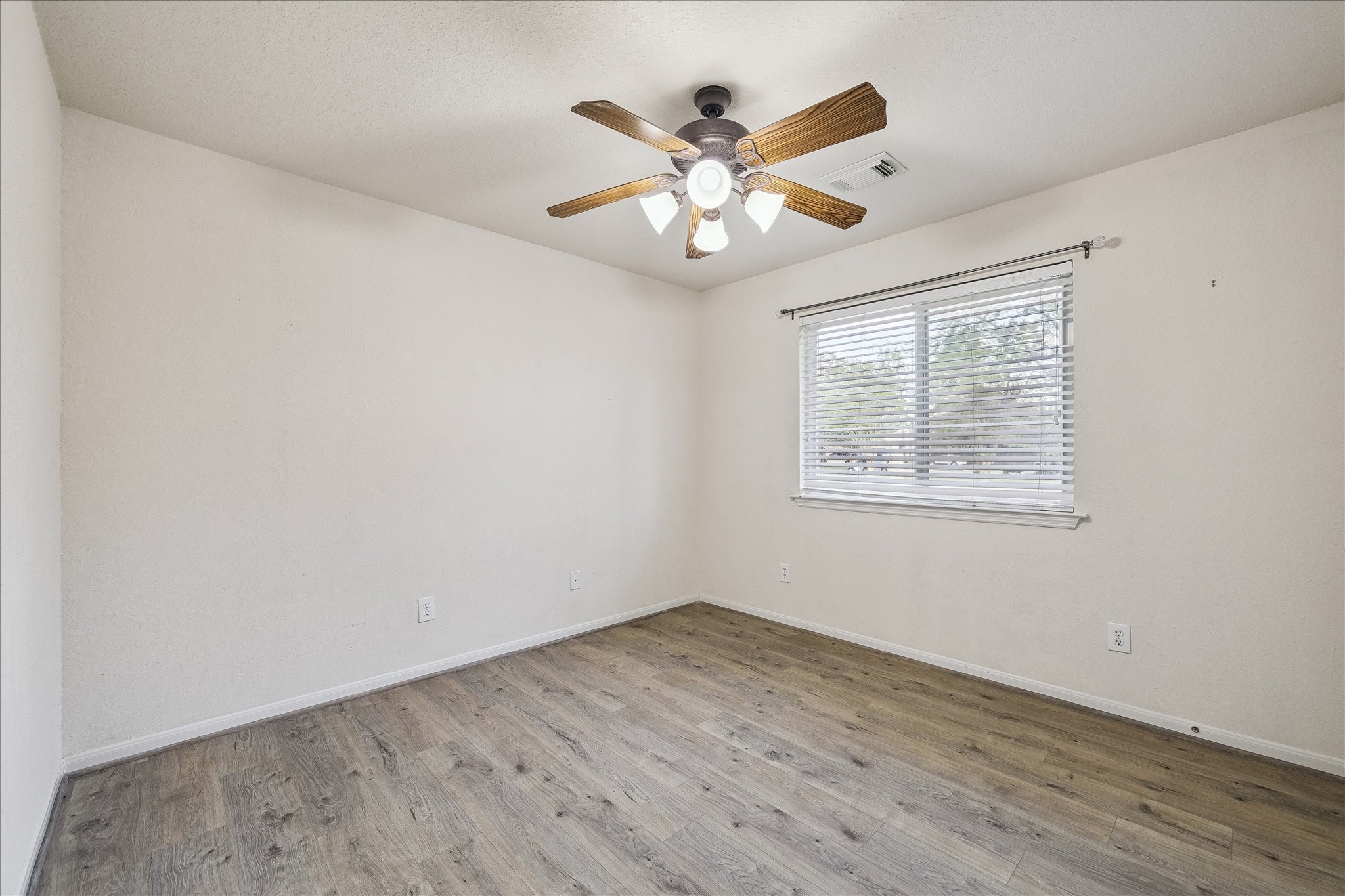 19403 Valiant Woods Drive Spring, TX 77379 - Photo 36 of 42 an empty room with wooden floor fan and windows