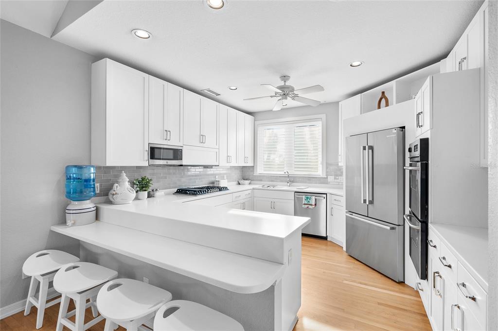 319 Pilot Point Lane Boca Grande, FL 33921 - Photo 12 of 62 a large white kitchen with a refrigerator a stove a sink dishwasher and a refrigerator with wooden floor