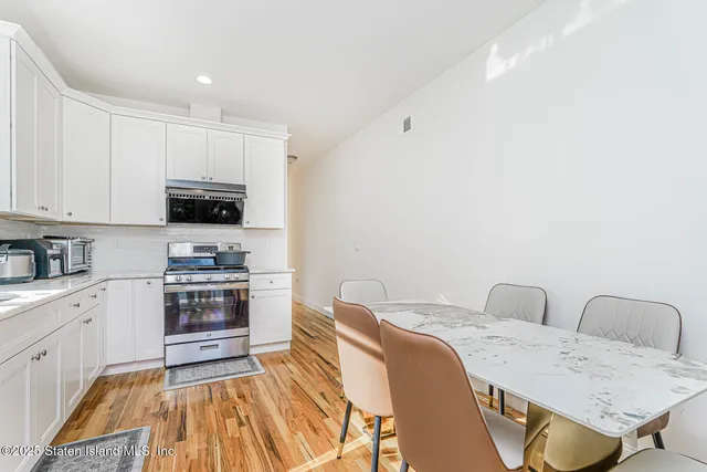a kitchen with stainless steel appliances white cabinets a sink a stove a refrigerator and a refrigerator