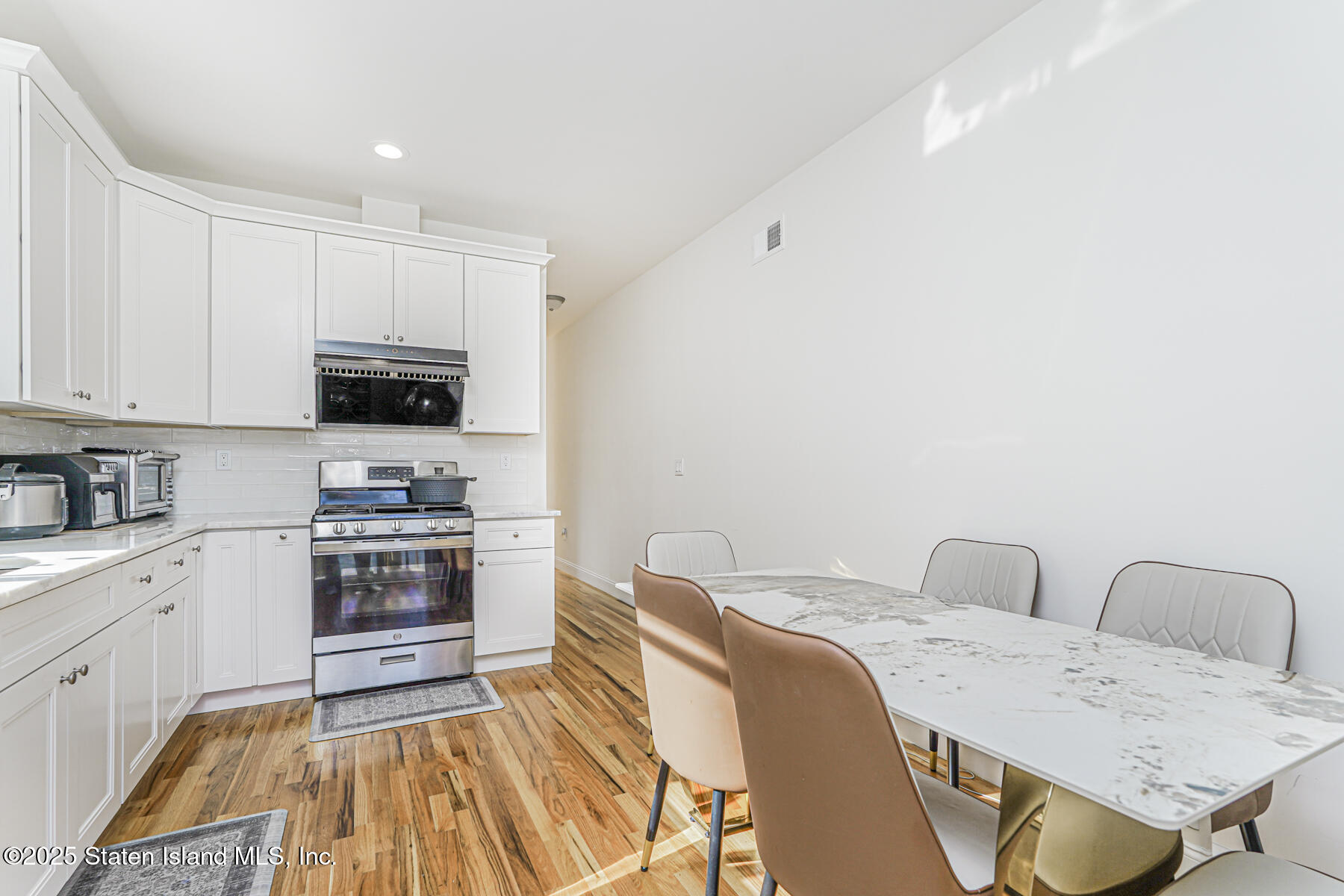 25 Ardmore Avenue Staten Island, NY 10314 - Photo 25 of 27 a kitchen with stainless steel appliances a stove top oven a sink dishwasher and white cabinets with wooden floor