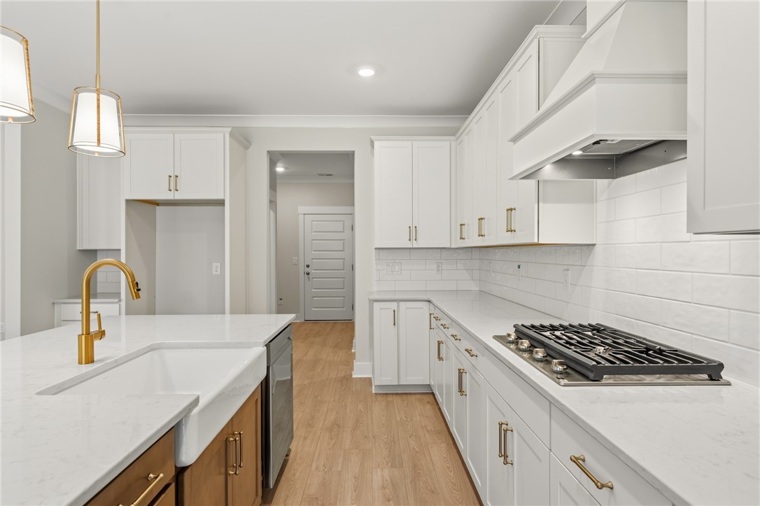 203 Timothy Court Anderson, SC 29621 - Photo 31 of 40 A pristine white kitchen features a large island with a farmhouse sink and modern gold fixtures, ready for culinary creations.