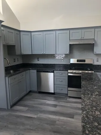 a kitchen with granite countertop a cabinets and white stainless steel appliances