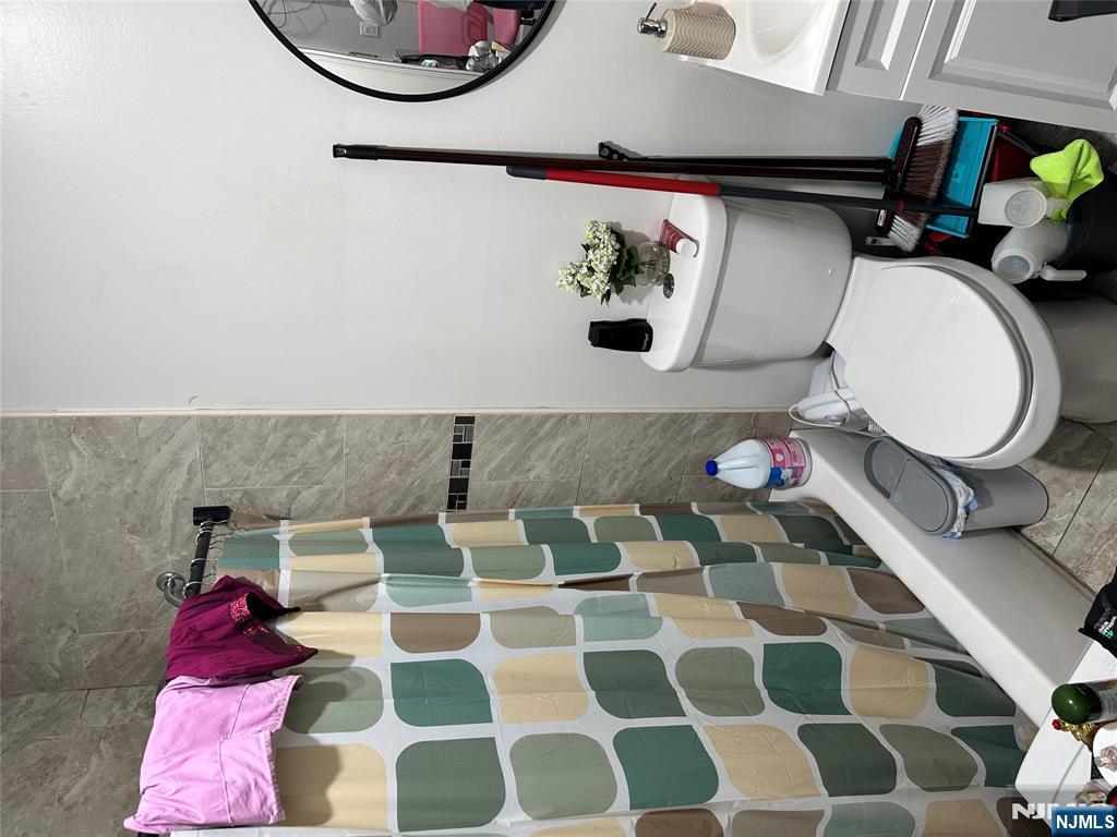 267 Ellison Street Paterson, NJ 07501 - Photo 14 of 16 a white toilet sitting next to a bathroom sink and a mirror