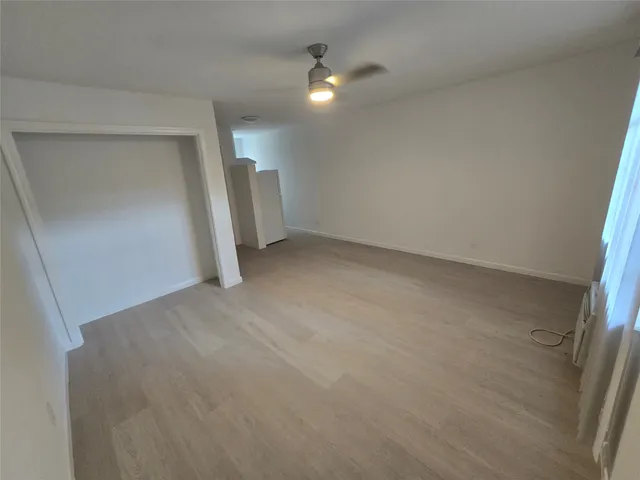 an empty room with closet and a ceiling fan