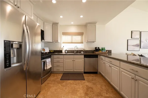 a kitchen with stainless steel appliances granite countertop a refrigerator sink and stove