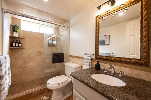 a bathroom with a granite countertop toilet sink and mirror
