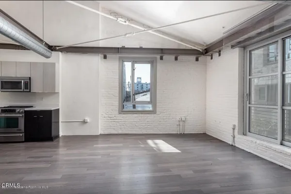 a view of an empty room with a kitchen and a window