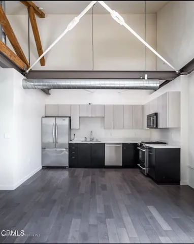 a living room with stainless steel appliances furniture and a kitchen view