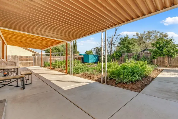 a patio with table and chairs and potted plants