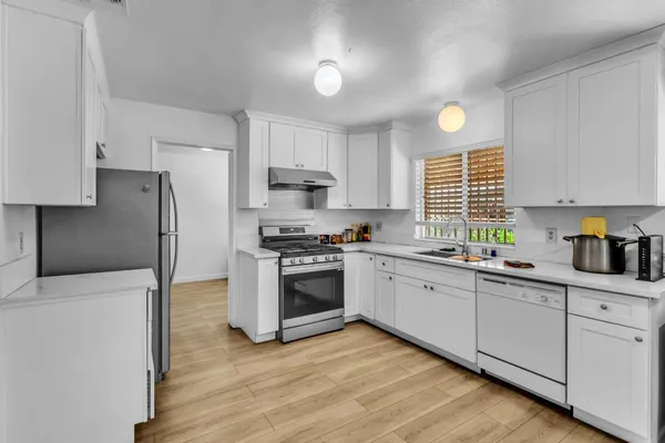 a kitchen with granite countertop a sink cabinets stainless steel appliances and a window