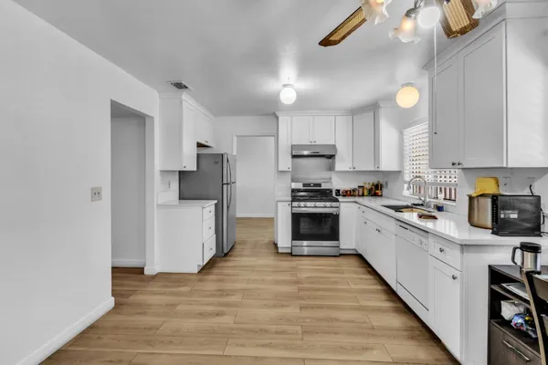 a kitchen with granite countertop a refrigerator and a stove top oven