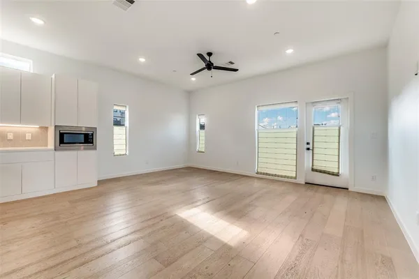 an empty room with wooden floor ceiling fan and windows