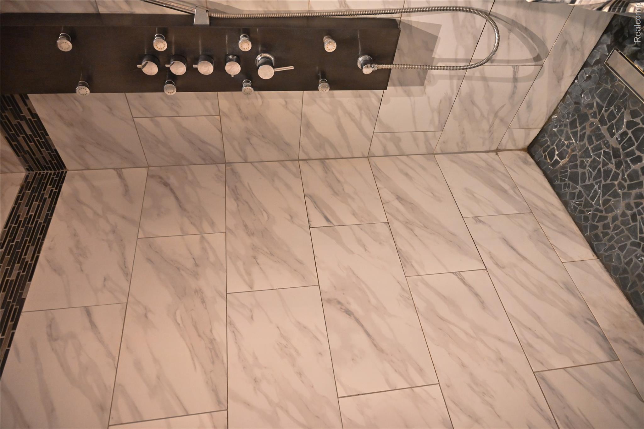 16501 Hannan Road Romulus, MI 48174 - Photo 15 of 20 Shower with large format marble-look wall tiles, mosaic accent border, and a dark stone-finish pebble tile floor