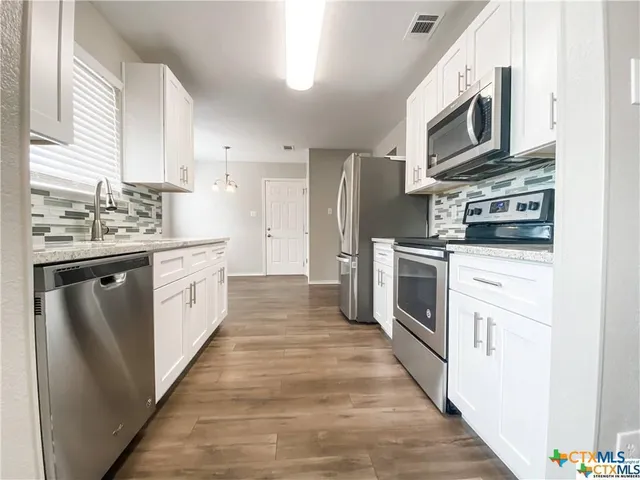 a kitchen with white cabinets stainless steel appliances and sink