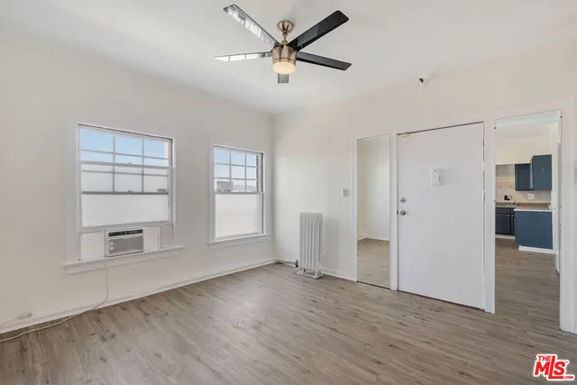 a view of empty room with wooden floor and ceiling fan