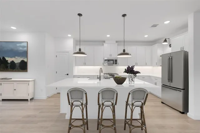 a kitchen with a sink stainless steel appliances and white cabinets