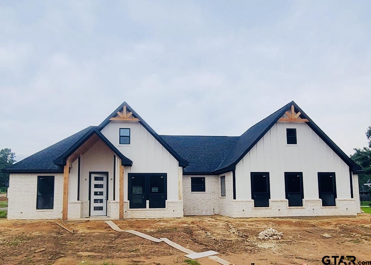 a view of a house with wooden walls and a yard