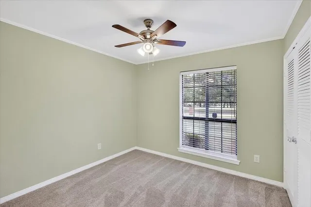 an empty room with ceiling fan and window