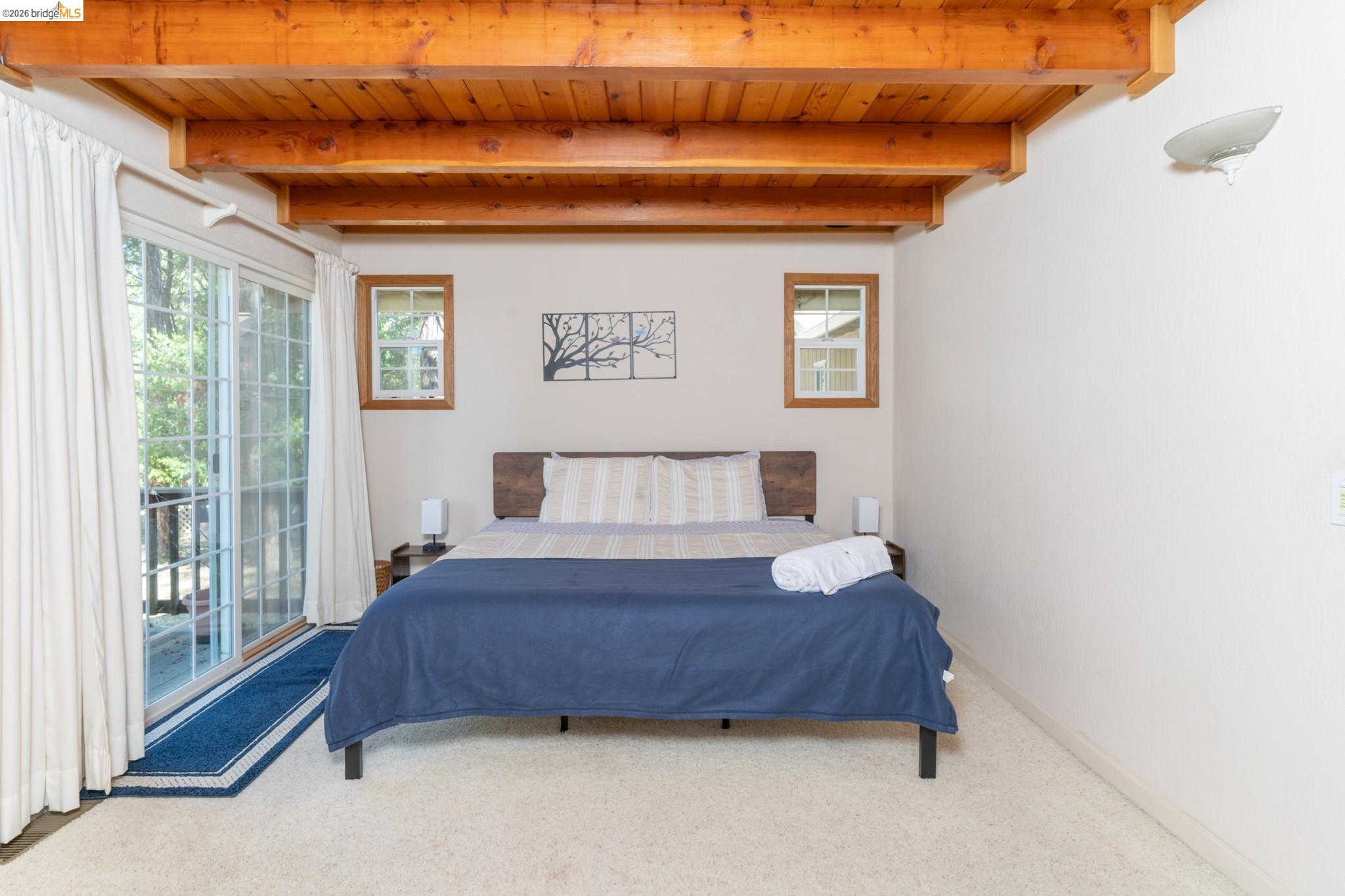 19390 Ferretti Road Groveland, CA 95321 - Photo 19 of 38 Exposed wood beam ceiling with wood paneling, sliding glass door, and two framed windows