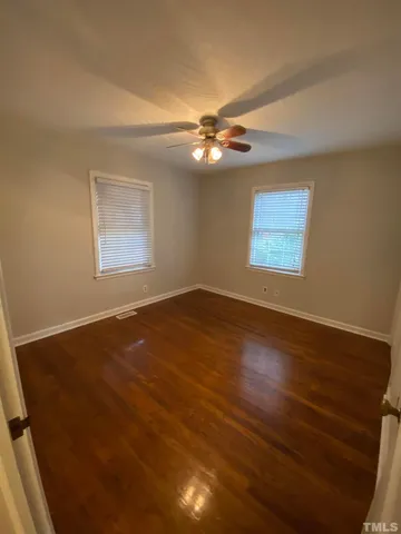 a view of empty room with wooden floor and fan