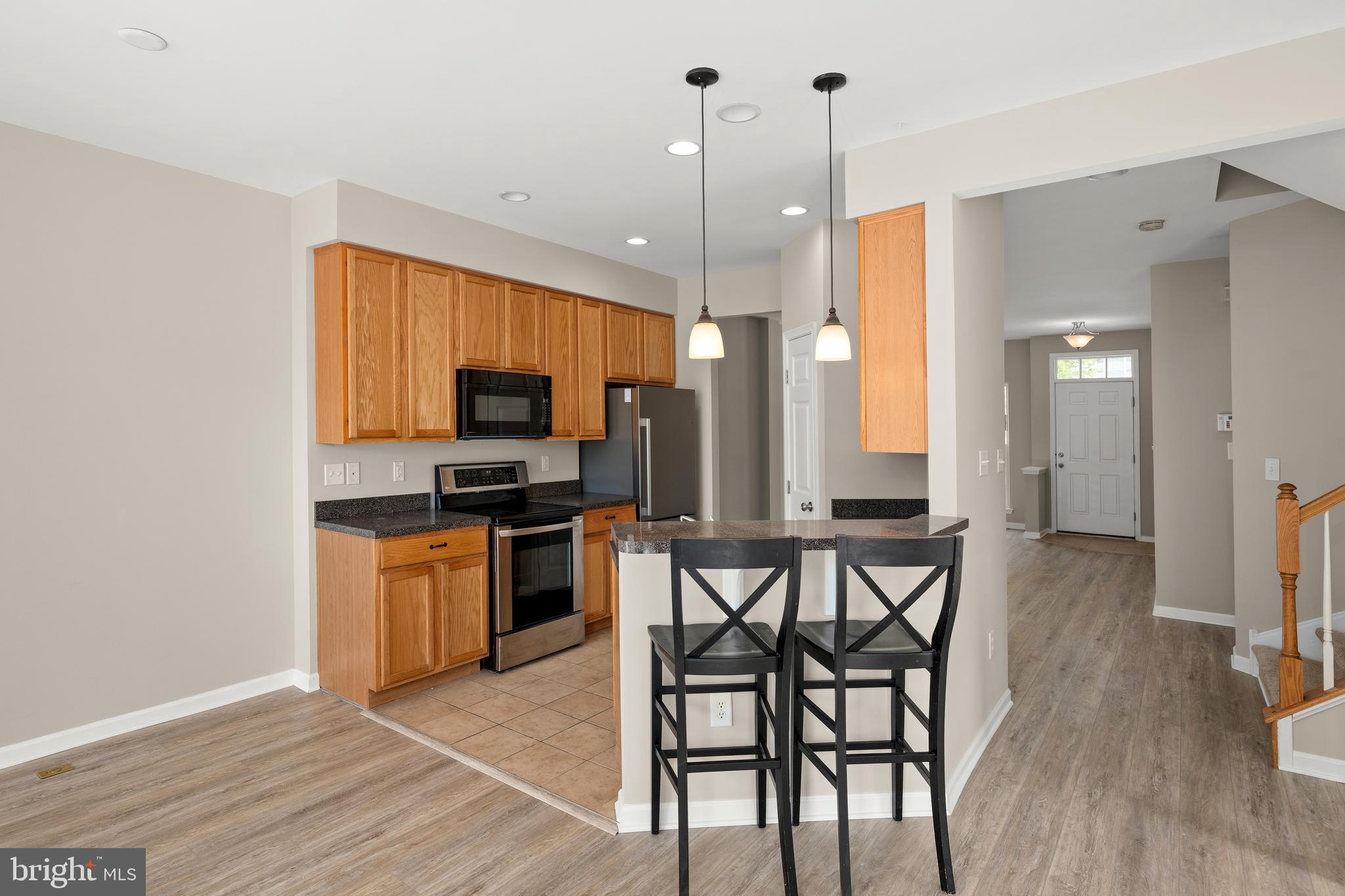 10023 Iron Pointe Drive Extension, Unit 201B2 Millsboro, DE 19966 - Photo 8 of 41 a kitchen with stainless steel appliances granite countertop a stove top oven a sink dishwasher a dining table and chairs with wooden floor
