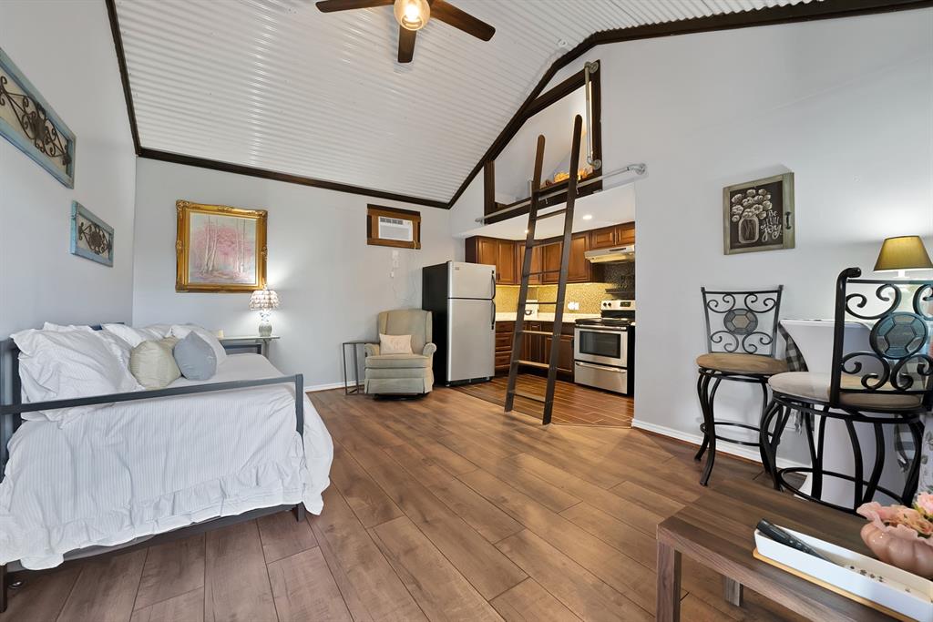306 Rochelle Boulevard Irving, TX 75062 - Photo 33 of 40 Vaulted corrugated metal ceiling, wood-finish flooring, kitchen area with wood cabinetry and stainless steel appliances, and a built-in loft with ladder access