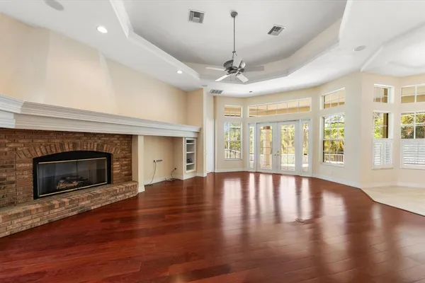 a view of an empty room with wooden floor fireplace and a window