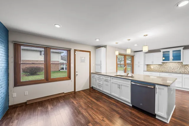 a large kitchen with stainless steel appliances granite countertop a large window a sink and cabinets