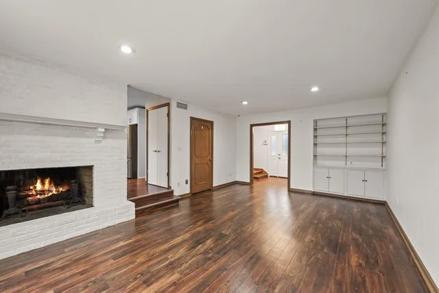 a view of an empty room with wooden floor fireplace and a window