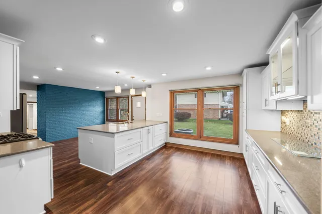 a living room with stainless steel appliances kitchen island hardwood floor and a large window