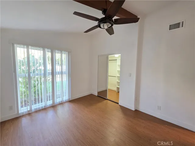 an empty room with wooden floor fan and windows