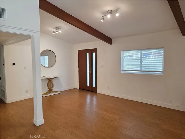 a view of an empty room with window and wooden floor