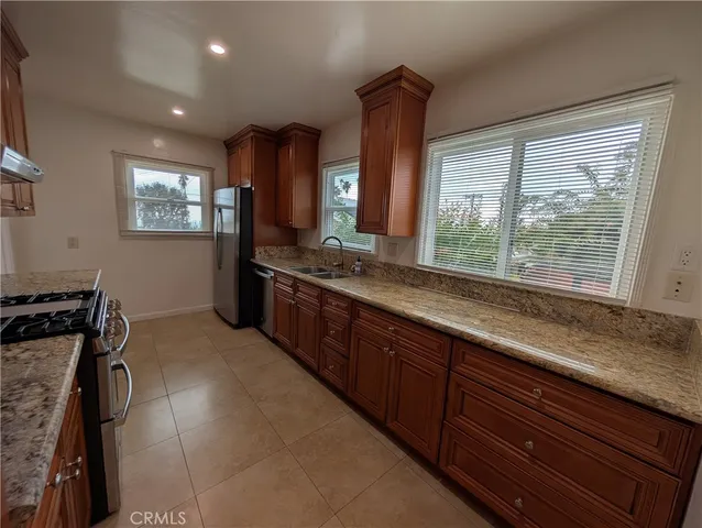 a kitchen with granite countertop stainless steel appliances a sink a stove top oven a washer dryer and a view of living room