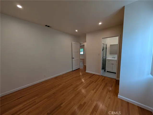 a view of a hallway with wooden floor and a bathroom