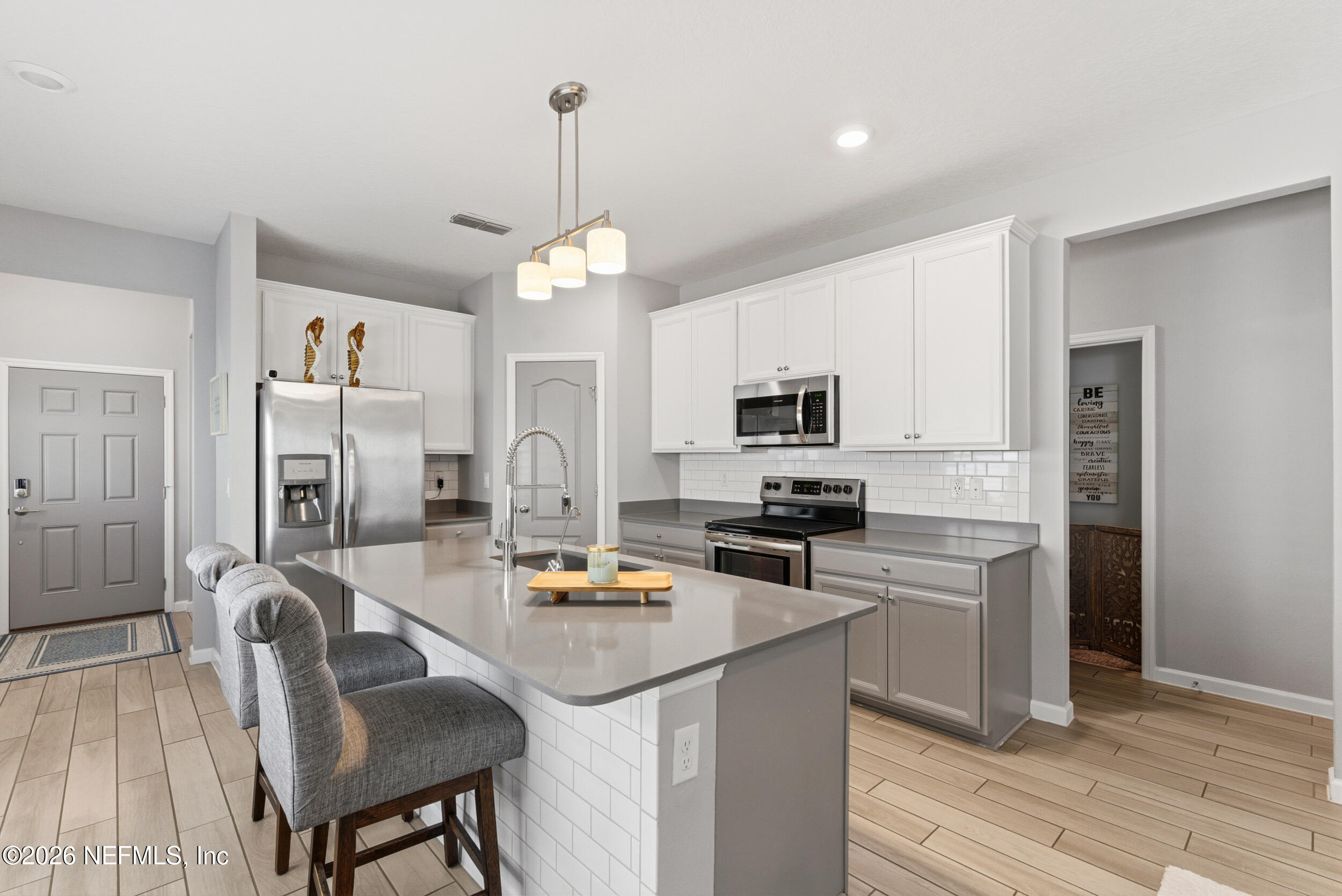 6507 Longleaf Branch Drive Jacksonville, FL 32222 - Photo 8 of 34 a open kitchen with stainless steel appliances granite countertop a stove top oven a refrigerator a kitchen island a dining table and chairs with wooden floor