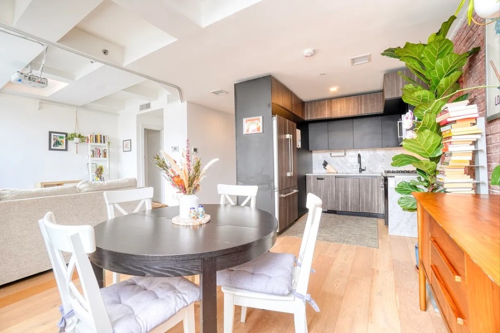 5-33 48th Avenue, Unit 4G Queens, NY 11101 - Photo 4 of 13 a living room with stainless steel appliances furniture a chandelier and a dining table