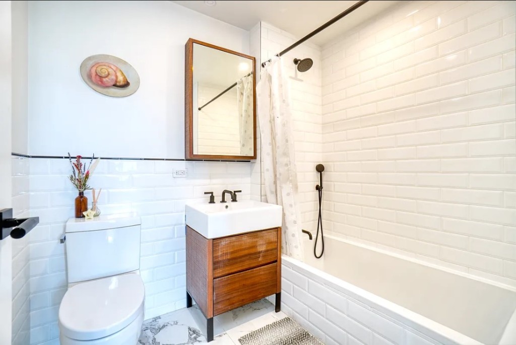 5-33 48th Avenue, Unit 4G Queens, NY 11101 - Photo 7 of 13 a bathroom with a toilet a sink and a bathtub
