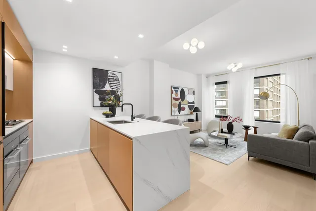 a living room with furniture a flat screen tv and a refrigerator