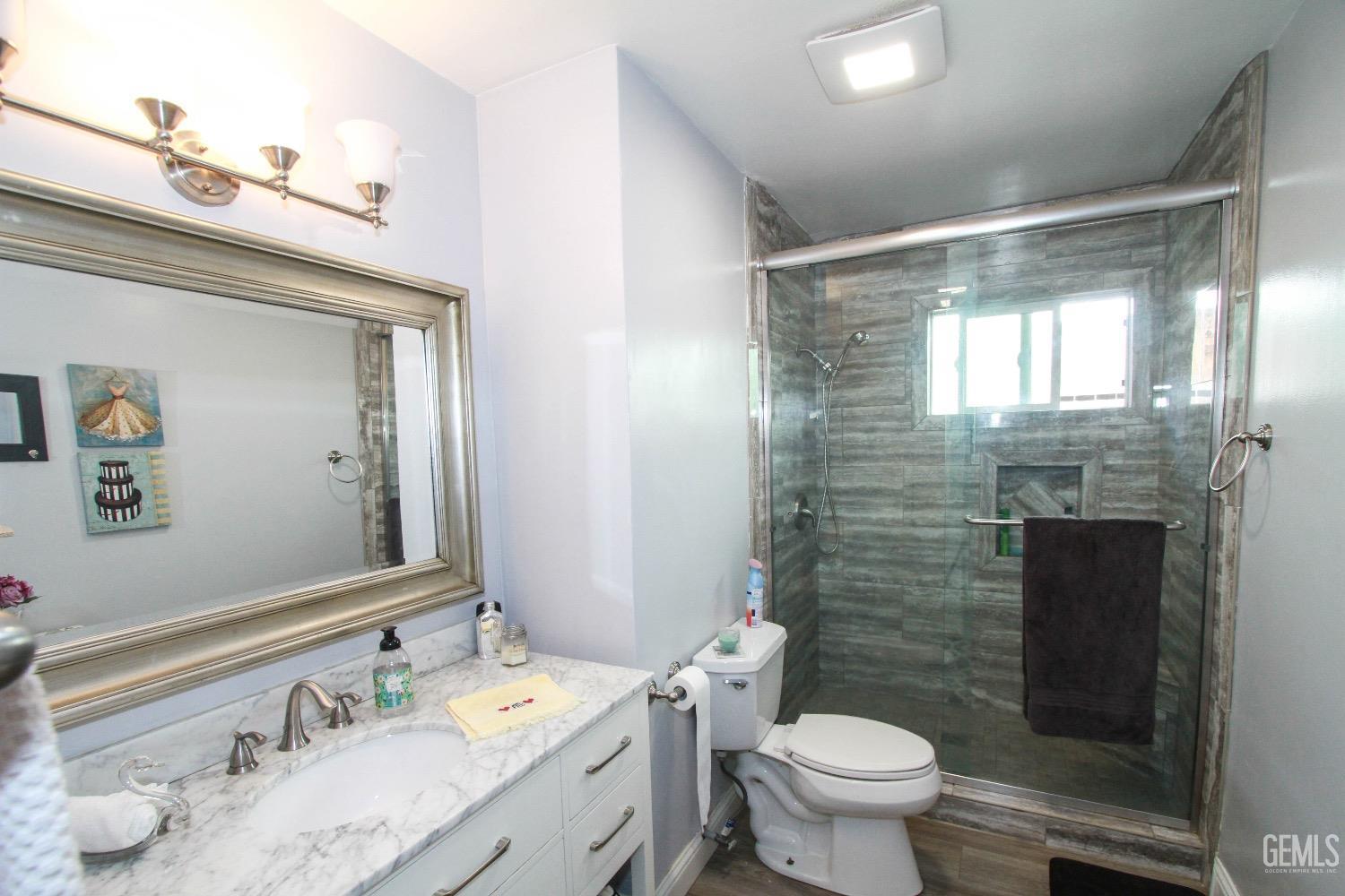 Undisclosed Address Bakersfield, CA 93306 - Photo 12 of 19 a bathroom with a granite countertop sink a large mirror a toilet and a shower