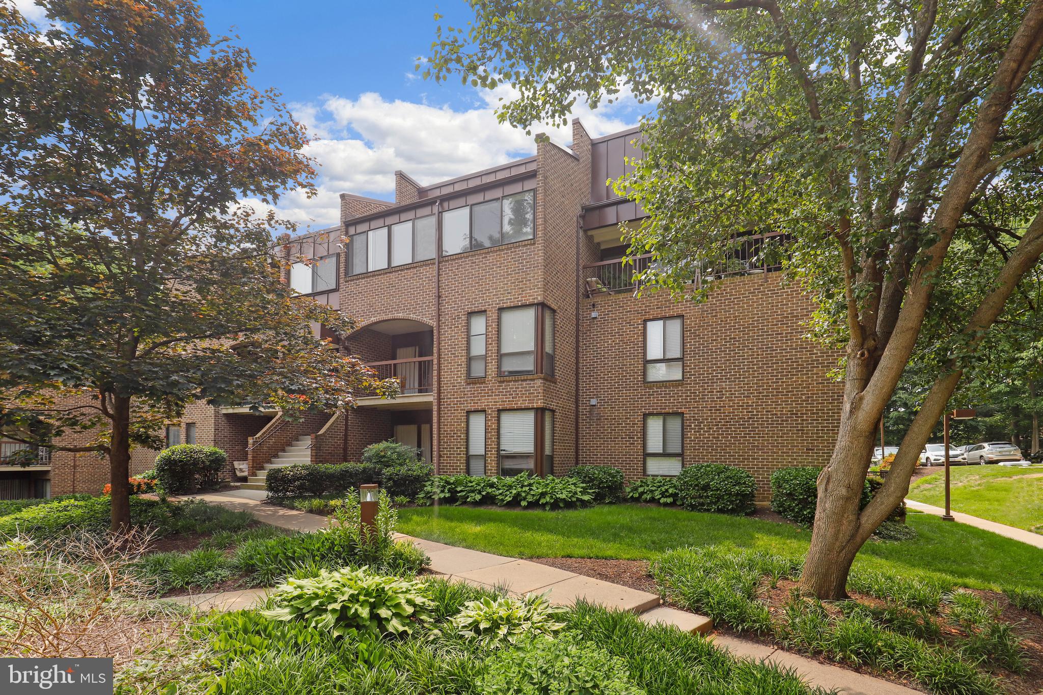 11216 Chestnut Grove Square, Unit 318 Reston, VA 20190 - Photo 1 of 32 a view of a brick house next to a yard with a large tree