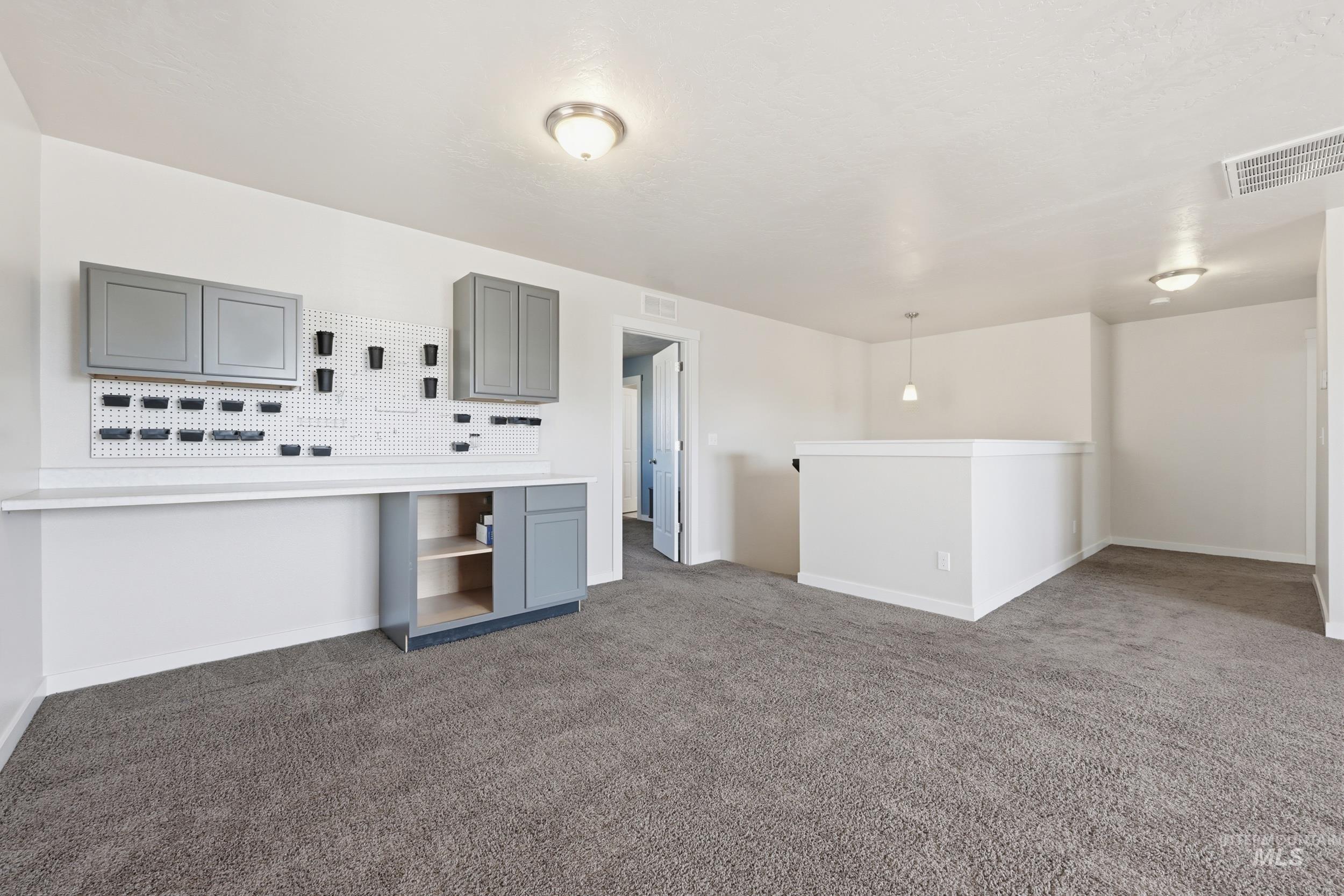 4855 South Chex Way Boise, ID 83709 - Photo 37 of 47 Spacious loft area featuring a built-in workstation with gray cabinetry, white countertop, and pegboard storage