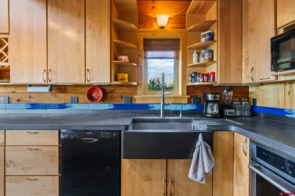 a kitchen with stainless steel appliances granite countertop a sink and a stove next to a large window