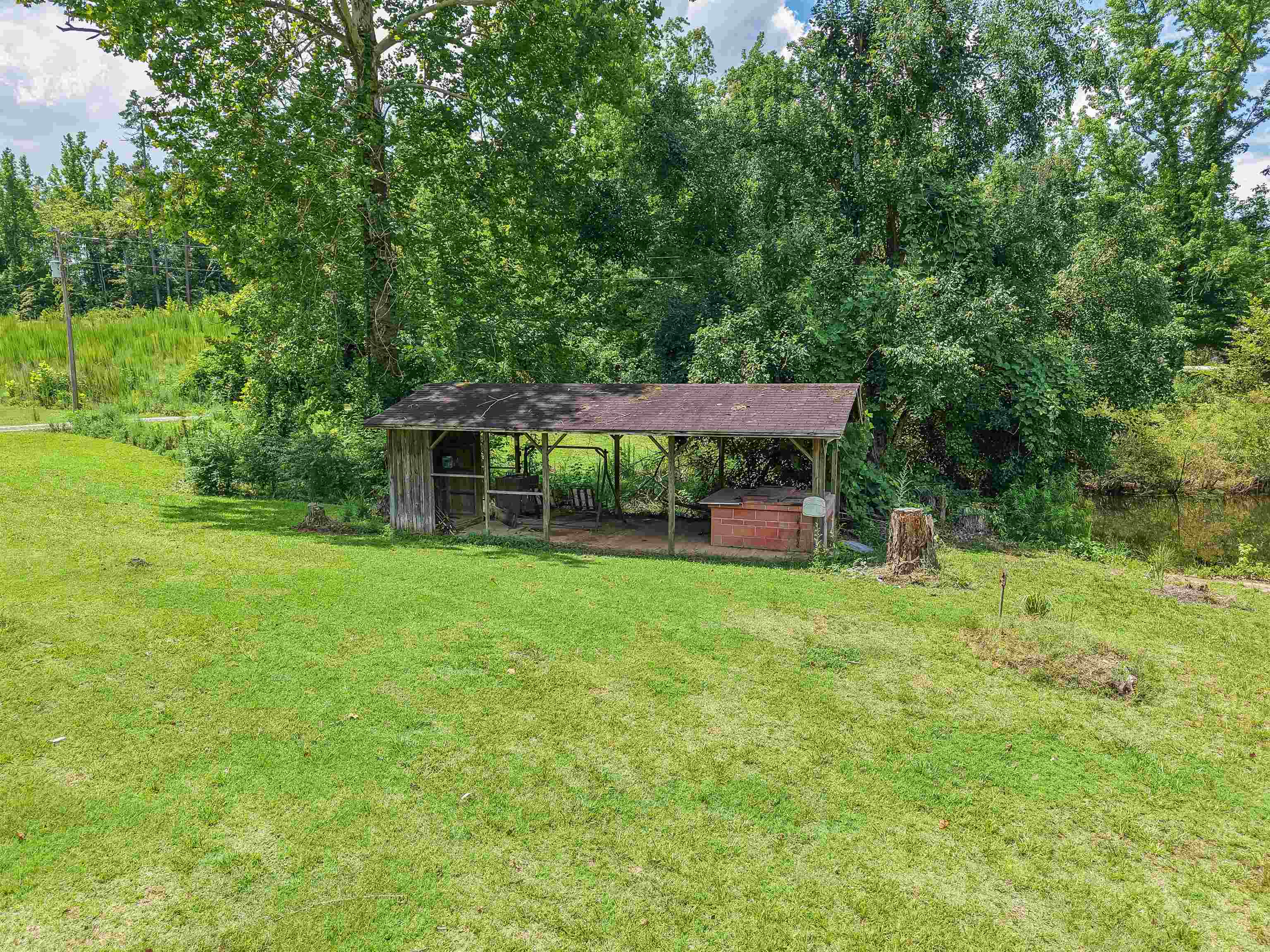 2380 Dunaway Road Selmer, TN 38375 - Photo 8 of 39 Expansive outdoor area featuring a rustic open-sided shed, a brick-built structure, and mature trees
