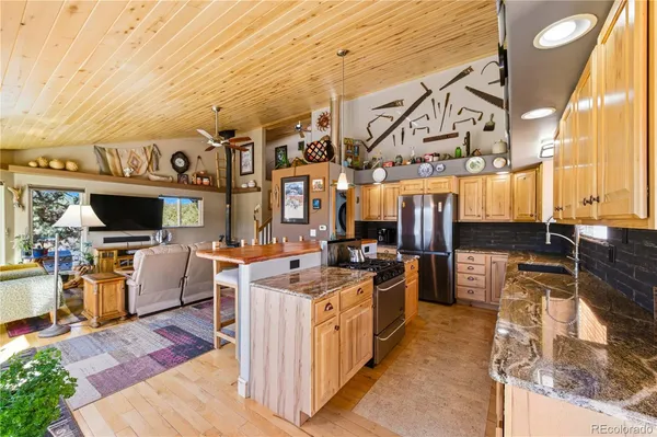 a view of a kitchen with stainless steel appliances kitchen island granite countertop a lot of counter top space