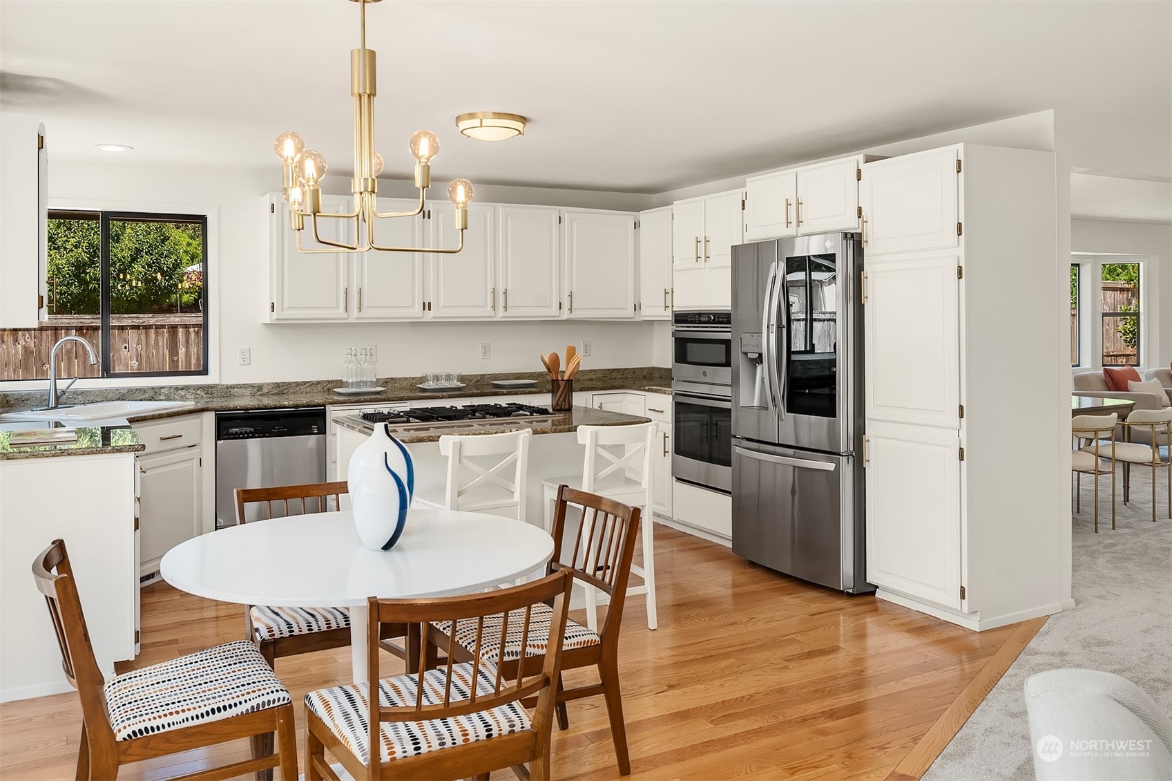 16254 Southeast 144th Street Renton, WA 98059 - Photo 9 of 29 a kitchen with stainless steel appliances a dining table chairs refrigerator and sink