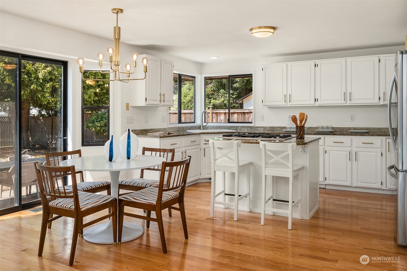 16254 Southeast 144th Street Renton, WA 98059 - Photo 10 of 29 a kitchen with stainless steel appliances granite countertop a stove top oven a sink a dining table and chairs with wooden floor