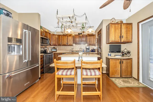 a kitchen with stainless steel appliances kitchen island granite countertop a refrigerator and cabinets