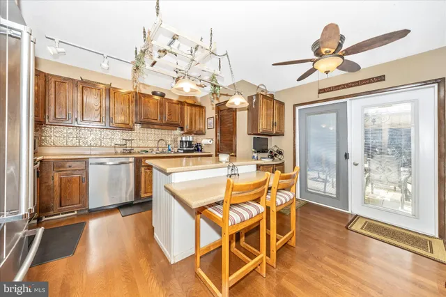 a kitchen with stainless steel appliances granite countertop a stove top oven a refrigerator a dining table and chairs with wooden floor