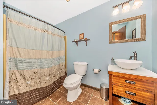 a bathroom with a granite countertop sink and a toilet