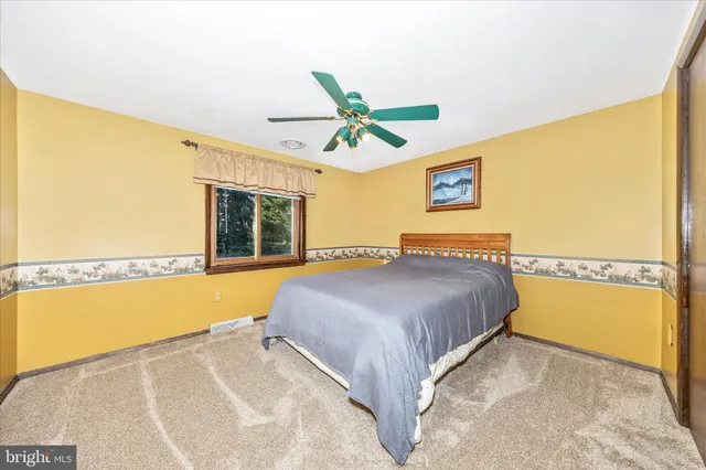a spacious bedroom with a bed a dresser and a window